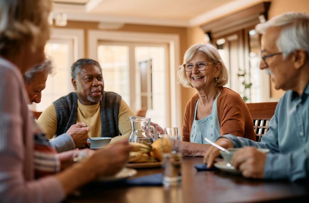 Seniors laughing and socializing while eating at a table.