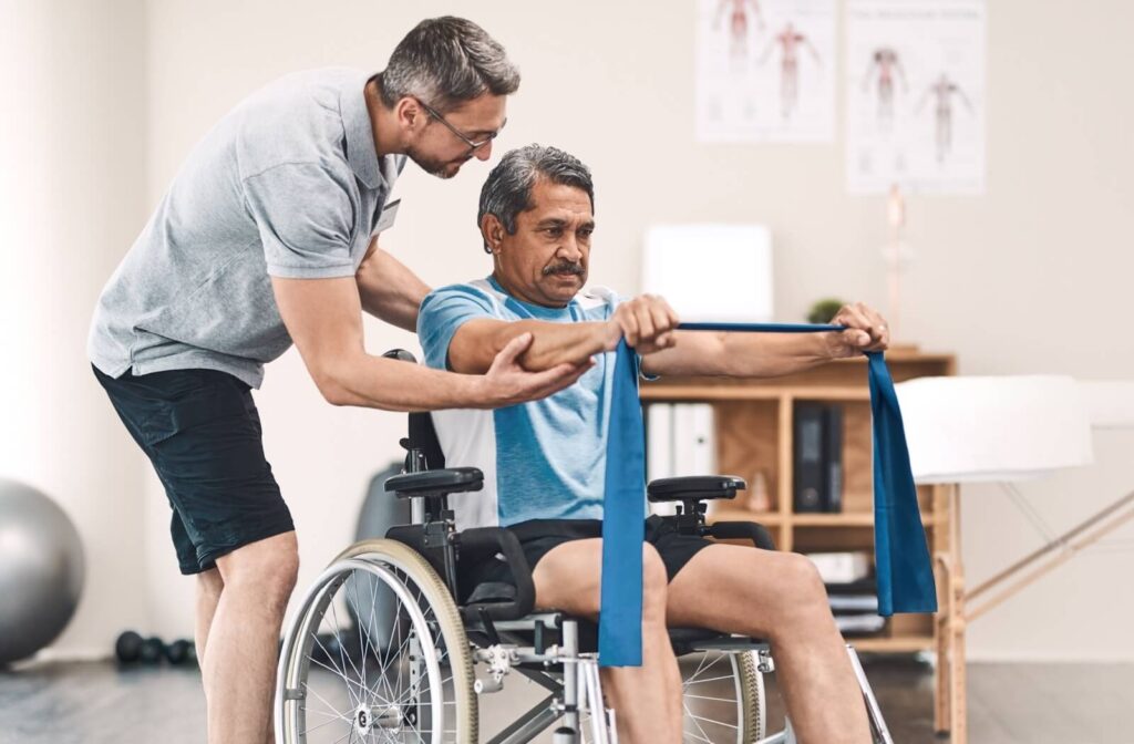 A person with a disability stretches with a resistance band and help from a physiotherapist.