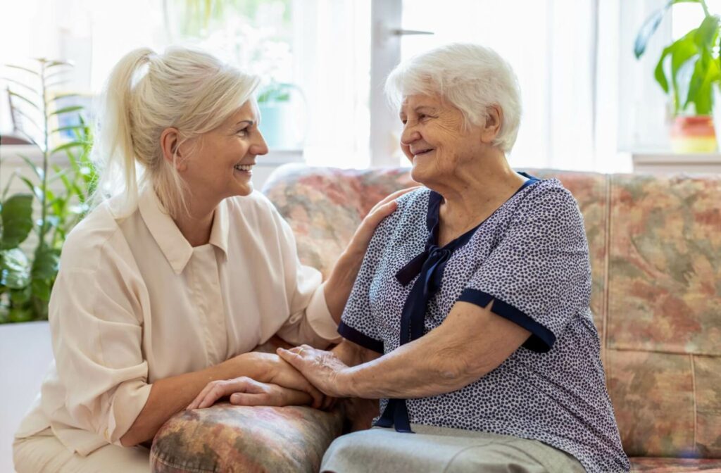 A senior and their adult child smile at each other
