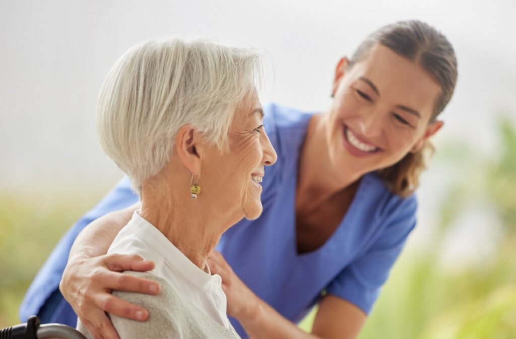 A caregiver reassures a smiling senior resident.