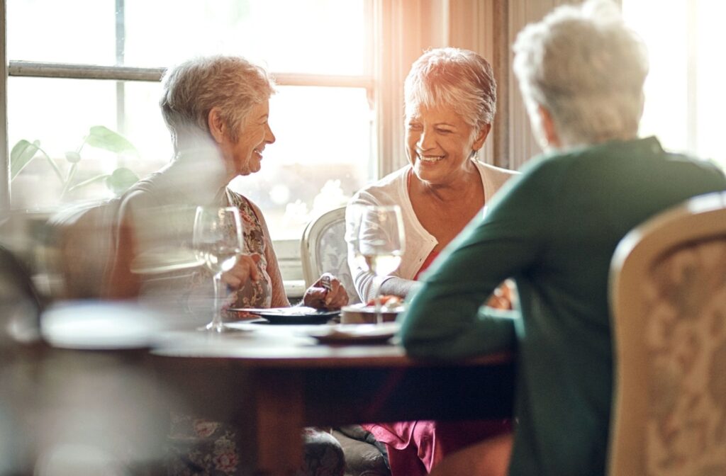 A group of senior friends laugh and reminisce over dinner at a senior living community.